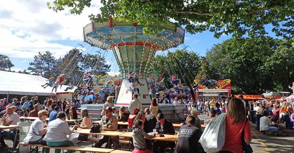 Das Karussel an der Bümplizer Chilbi. Im Vordergund Festbänke an welchen die Besucher konsumieren.